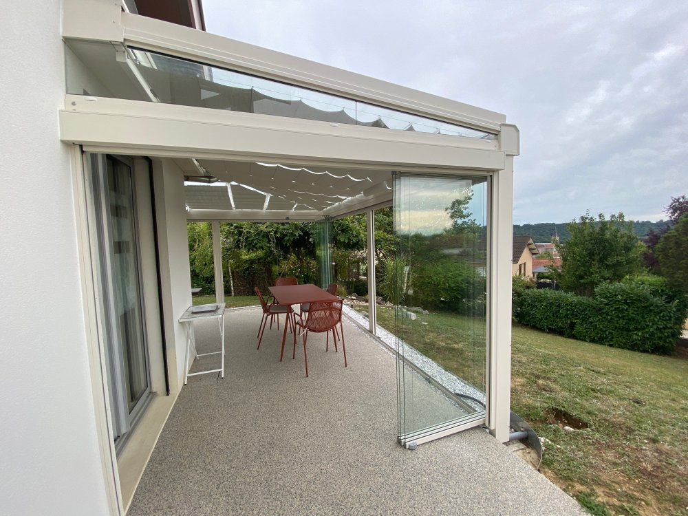 Installation d’une toiture vitrée sur-mesure et de coulissants pivotants : élégance et transparence pour une charmante maison dans l’Ain (01)