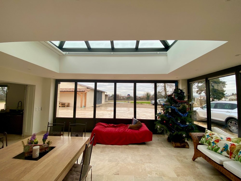 Rénovation et extension d’une habitation d’exception près de Villefranche-sur-Saône (69), intégrant des baies accordéon, une toiture vitrée et des stores sur-mesure.