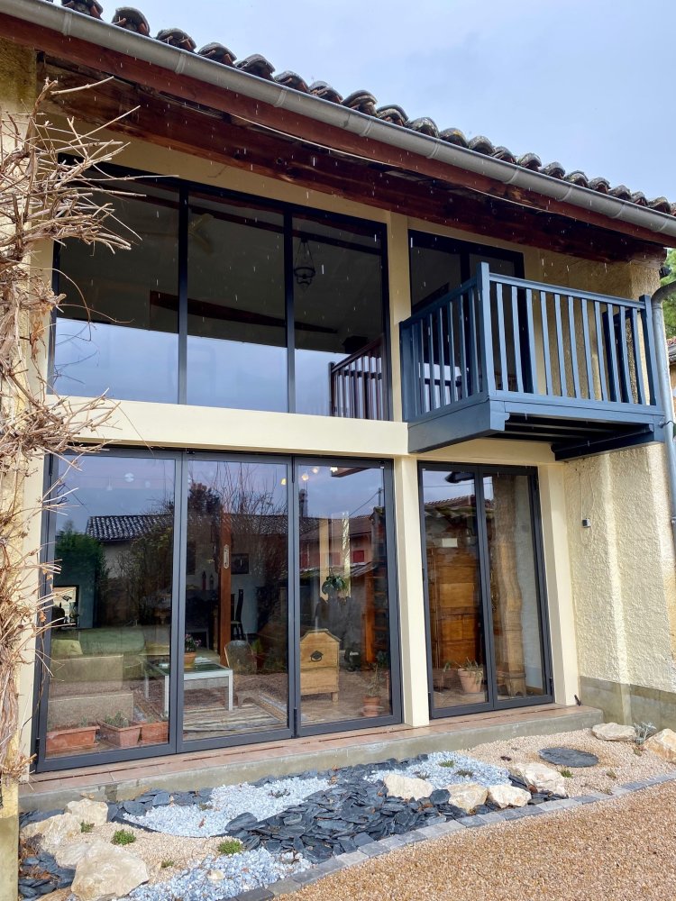 Pose sur-mesure de baies accordéon et d'un châssis fixe dans une charmante maison située dans l'Ain