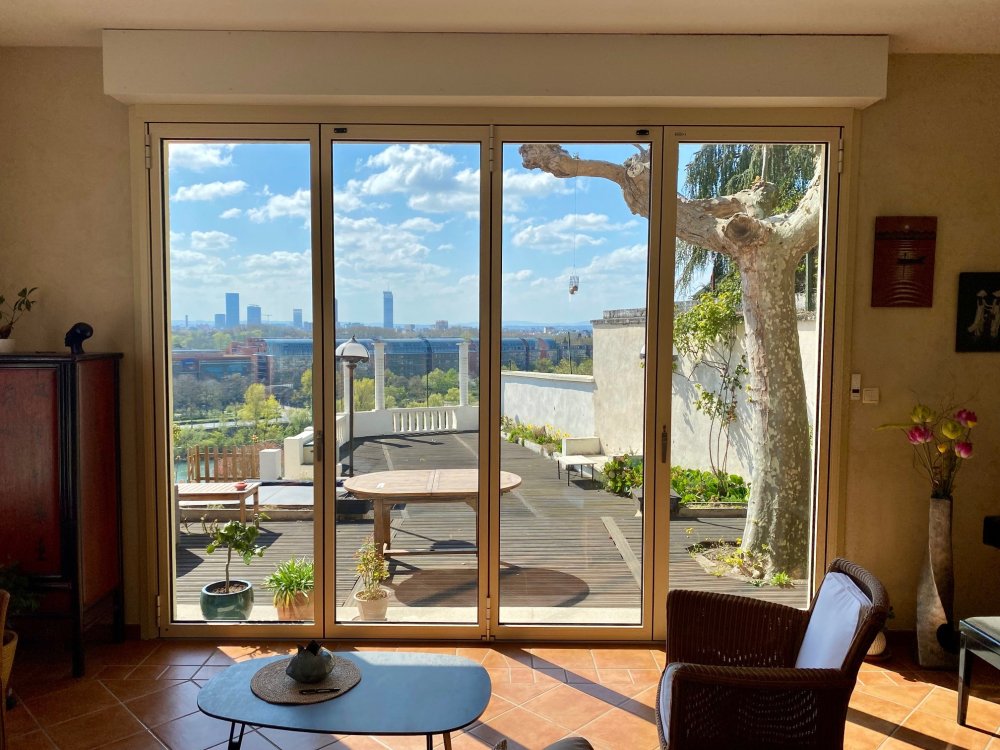 Remplacement d’une baie accordéon en bois par un modèle en aluminium dans une villa surplombant Lyon. 