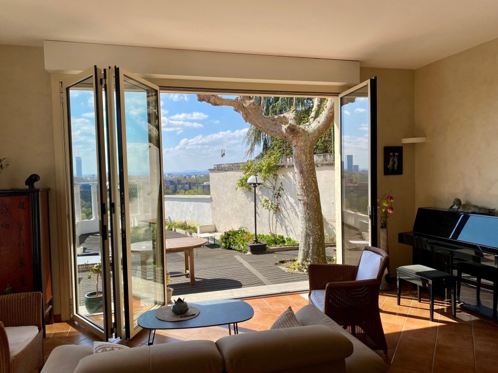 Remplacement d’une baie accordéon en bois par un modèle en aluminium dans une villa surplombant Lyon. 