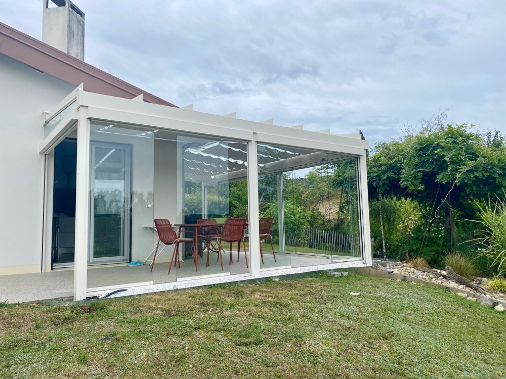Installation d’une toiture vitrée sur-mesure et de coulissants pivotants : élégance et transparence pour une charmante maison dans l’Ain (01)