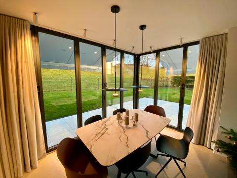 Splendide extension de pièce de vie réalisée grâce à une baie accordéon d’angle, offrant une ouverture maximale sur l’extérieur.